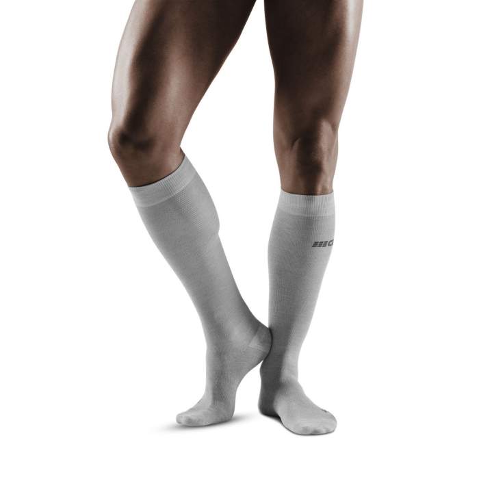 Lower legs of male model wearing knee-high CEP AllDay recovery compression socks in light grey.