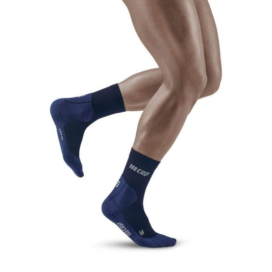 Lower legs of male model running in mid-cut CEP Cold Weather compression socks in navy.