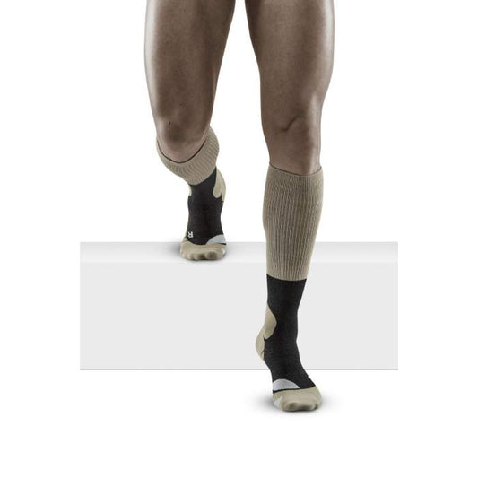 Lower legs of male model walking in knee-high CEP Hiking Merino compression socks in sand grey.