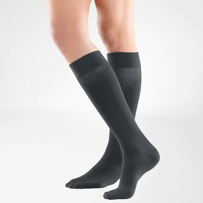 A model wearing knee-high anthracite Bauerfeind VenoTrain Look compression socks.