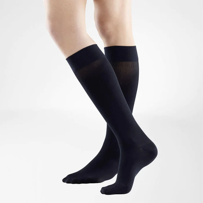 A model wearing knee-high black Bauerfeind VenoTrain Look compression socks.