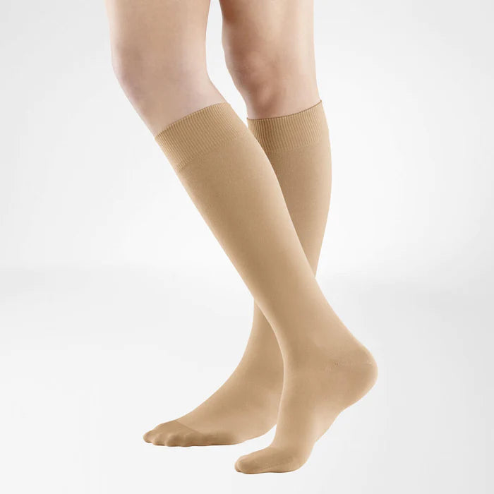 A model wearing knee-high caramel Bauerfeind VenoTrain Look compression socks.
