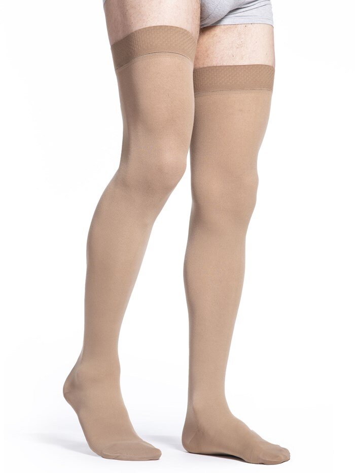 Legs of male model in thigh-high Sigvaris Cotton compression tights in light beige.