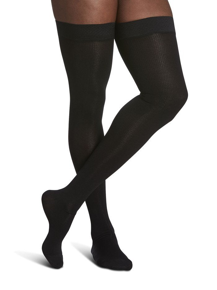 Legs of female model in thigh-high Sigvaris Cotton compression tights in black.