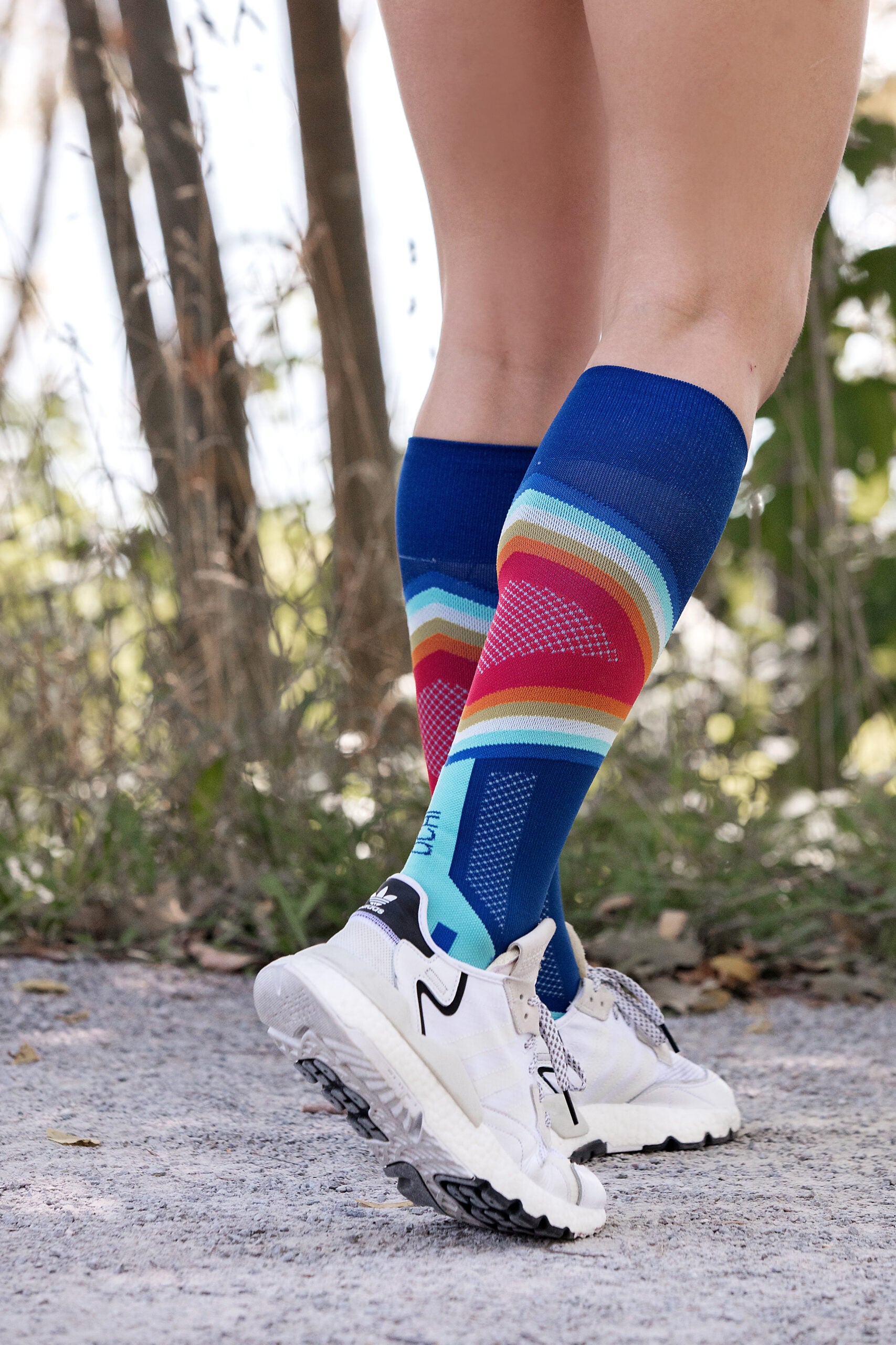 Lower legs of a female model in Lunatik Propel Elite compression socks and white running shoes.