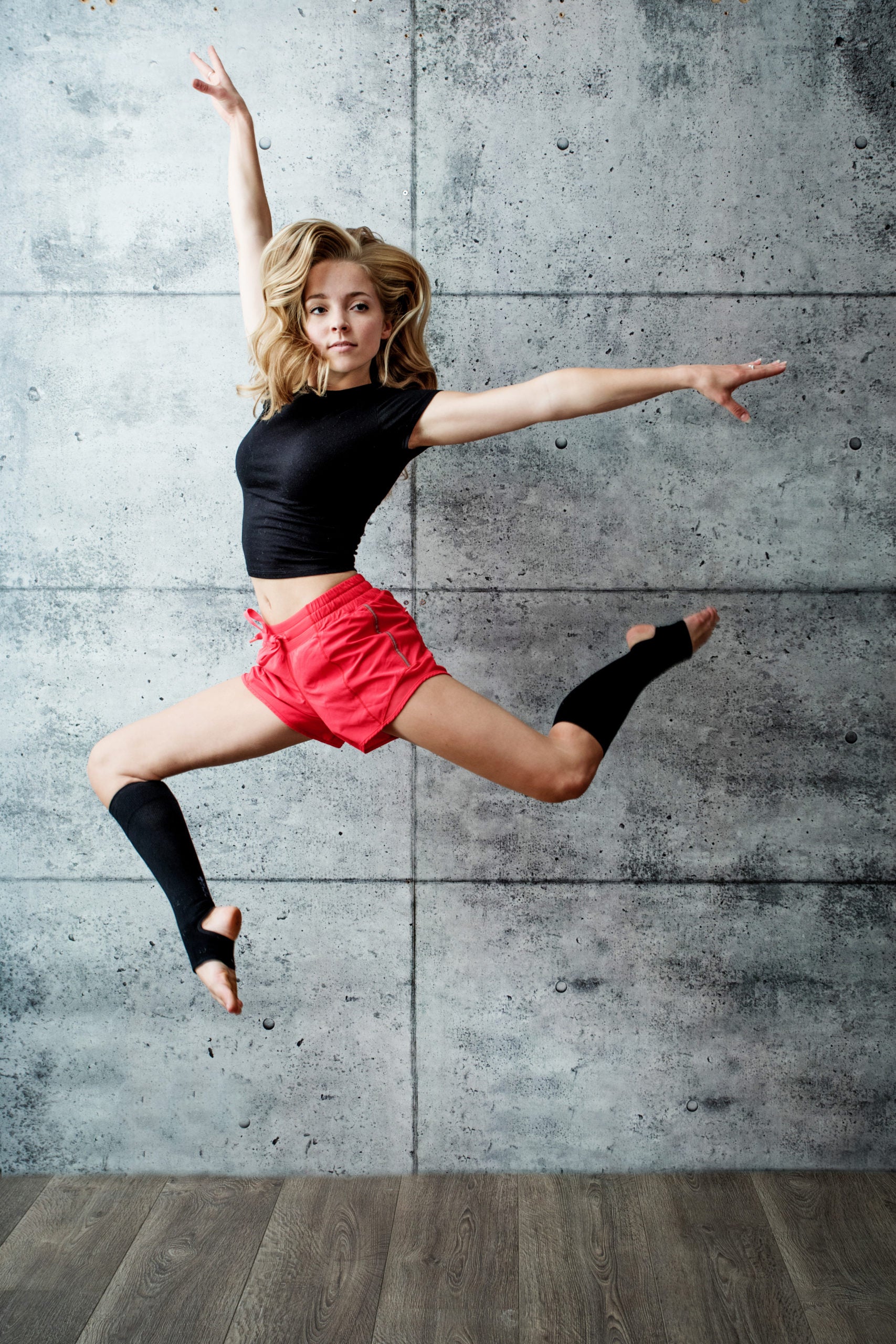 Dancer, mid-jump, wearing Lunatik Stirr Up compression socks (cropped toe and heel).