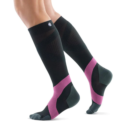 Lower legs of a model in charcoal pink Bauerfeind training compression socks standing in front of a white background.
