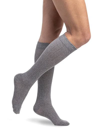 Legs of model in Sigvaris Linen compression calf socks in grey.