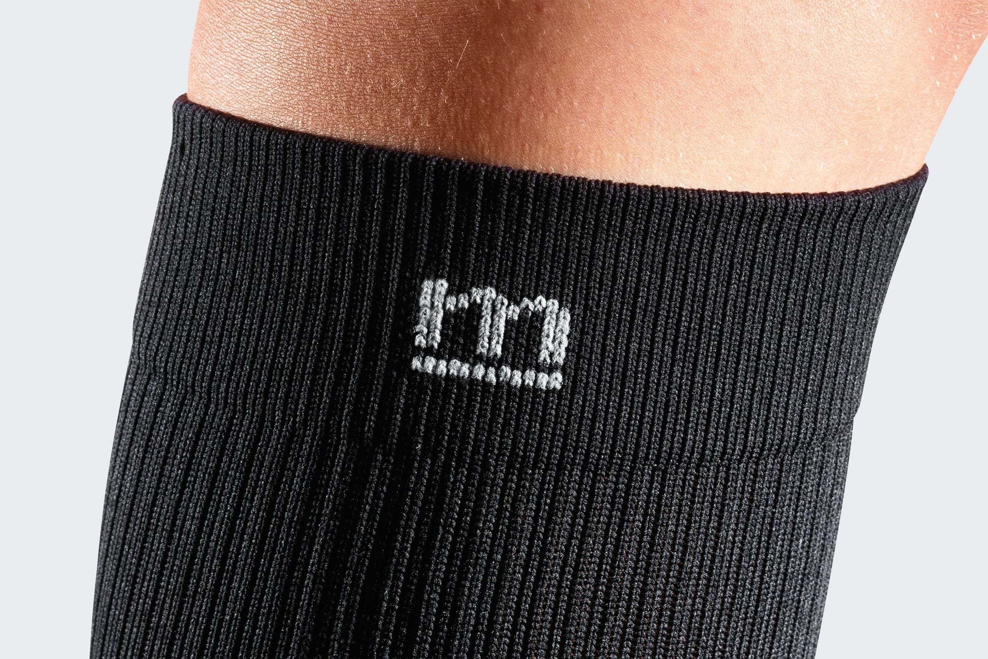 Close-up of the Mediven logo on black compression socks.