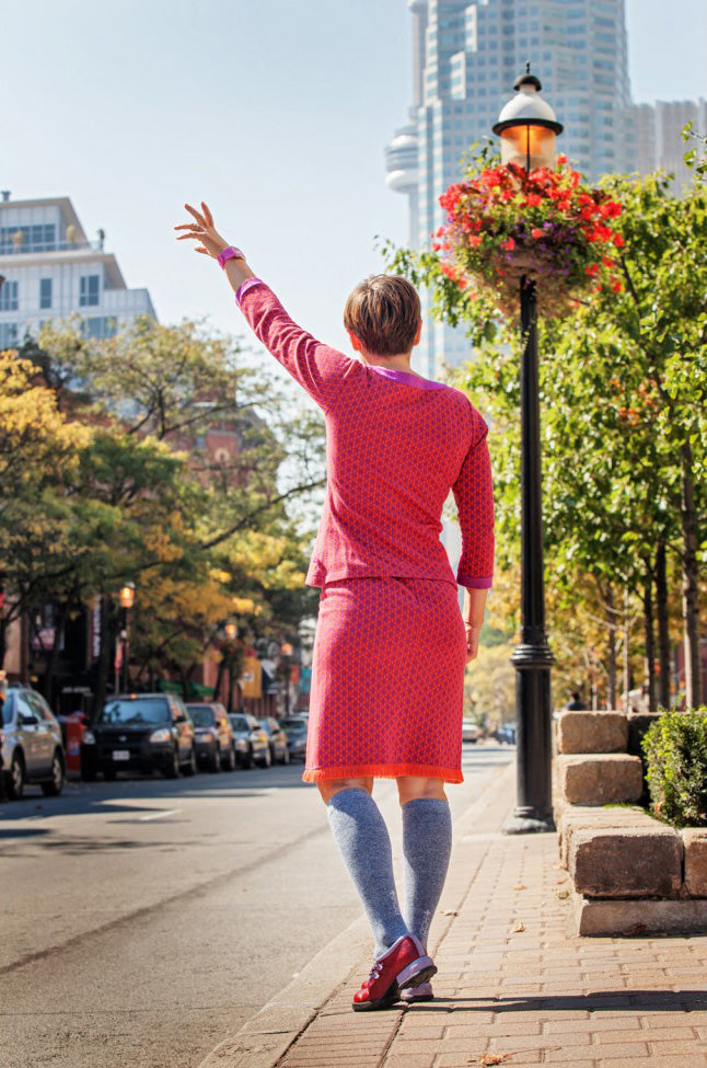 Woman hailing down a cab in bright pink outfit and Lunatik Denim Cool compression socks.