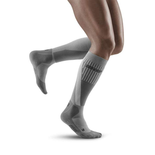 Lower legs of male model running in knee-high CEP Cold Weather compression socks in grey.