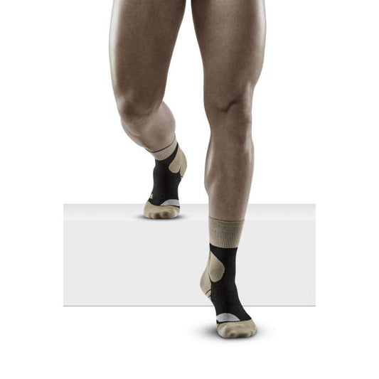 Lower legs of male model walking in mid-cut CEP Hiking Merino compression socks in sand grey.