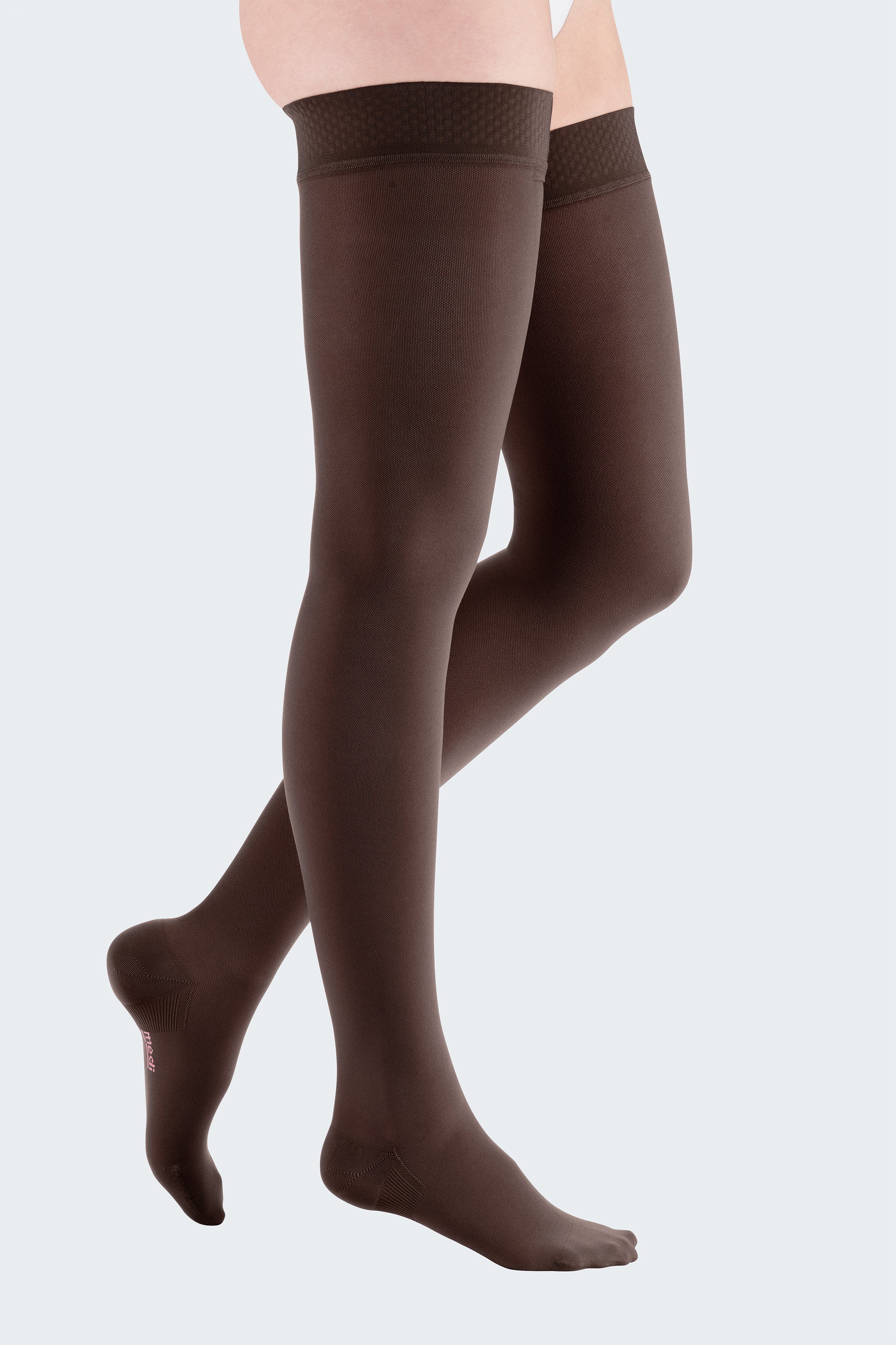 Lower body of female model in thigh-length Mediven Elegance compression tights in chestnut brown.
