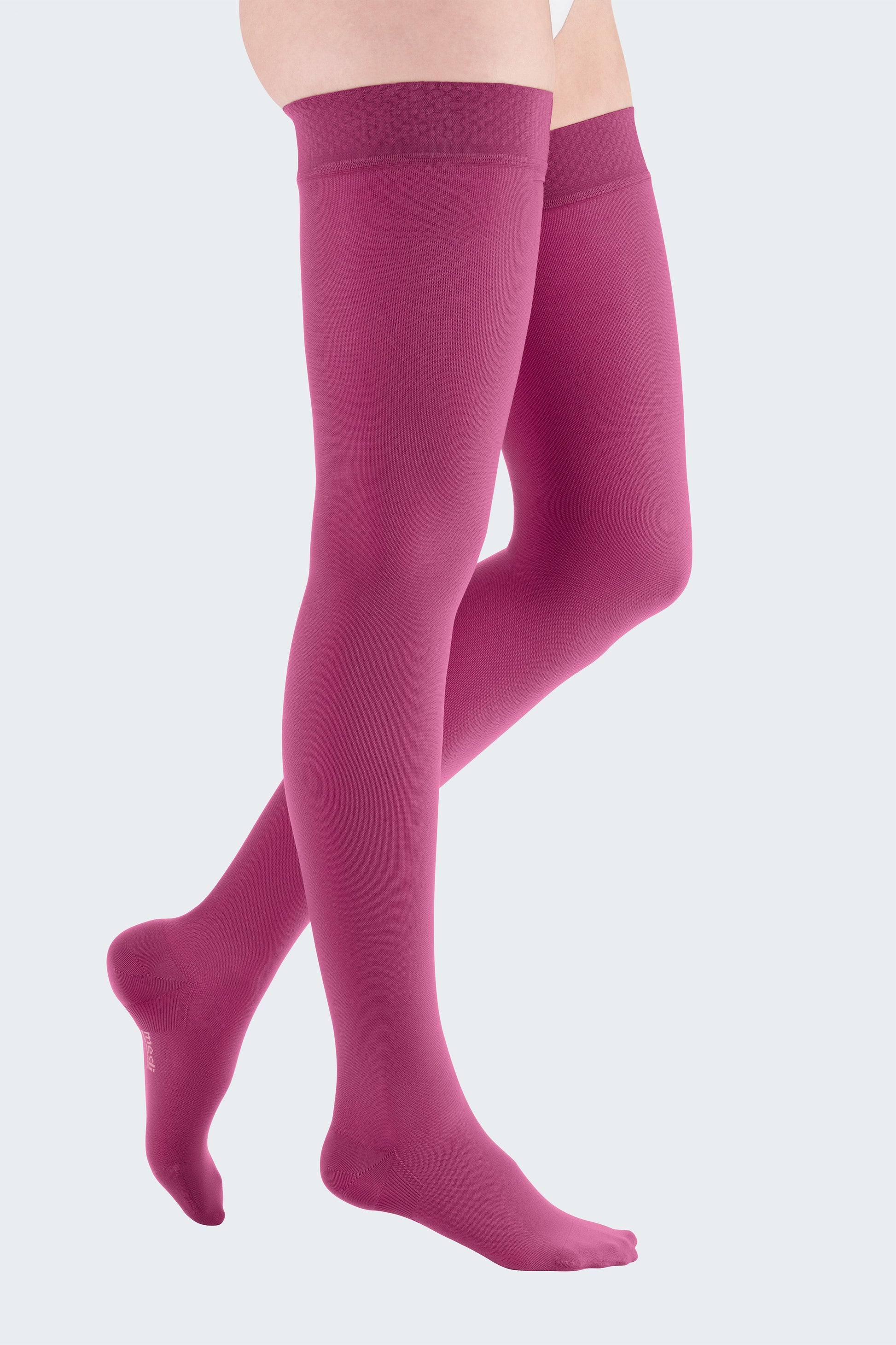 Lower body of female model in thigh-length Mediven Elegance compression tights in raspberry red.