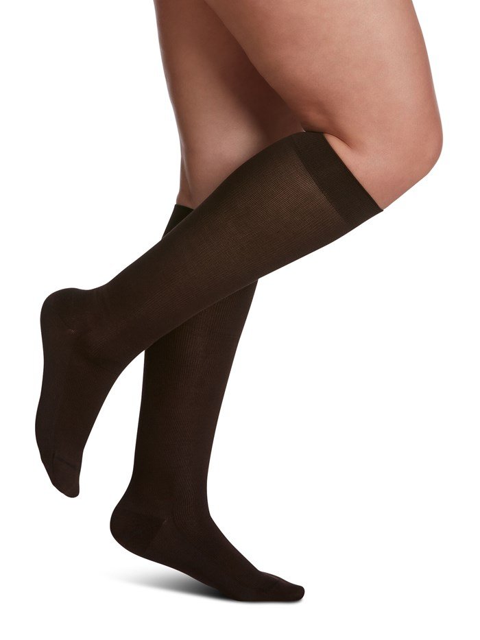 Legs of female model in Sigvaris Sea Island Cotton compression socks in brown.